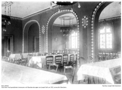 Foto eines frisch gestalteten Innenraums mit Wandverzierungen von Joseph Stoll um 1910, vermutlich Bensheim. Die als Bordüre und Türverzierungen angebrachten Malereien im Jugendstil finden sich auch in ähnlichen Ausführungen an Bensheimer Fassaden.
